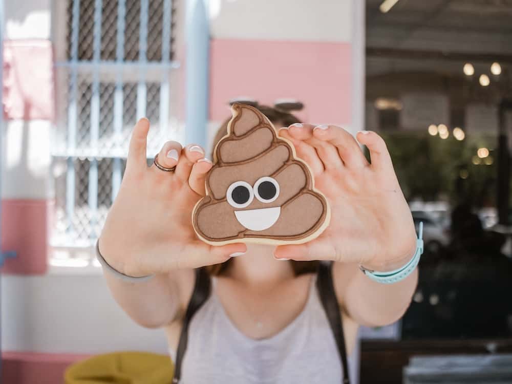 A woman holds up a poop emoji.