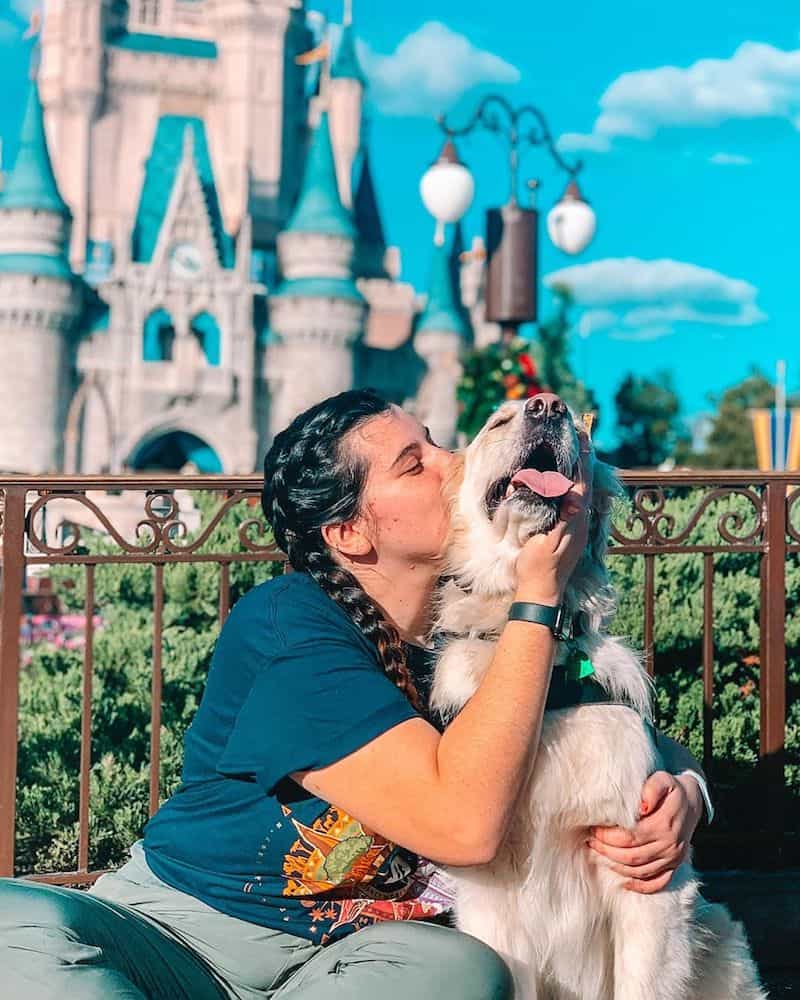 A girl kisses a dog at Disney World.