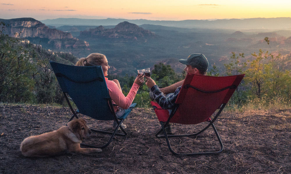 Two people enjoying a glass of wine with a dog at their feet.